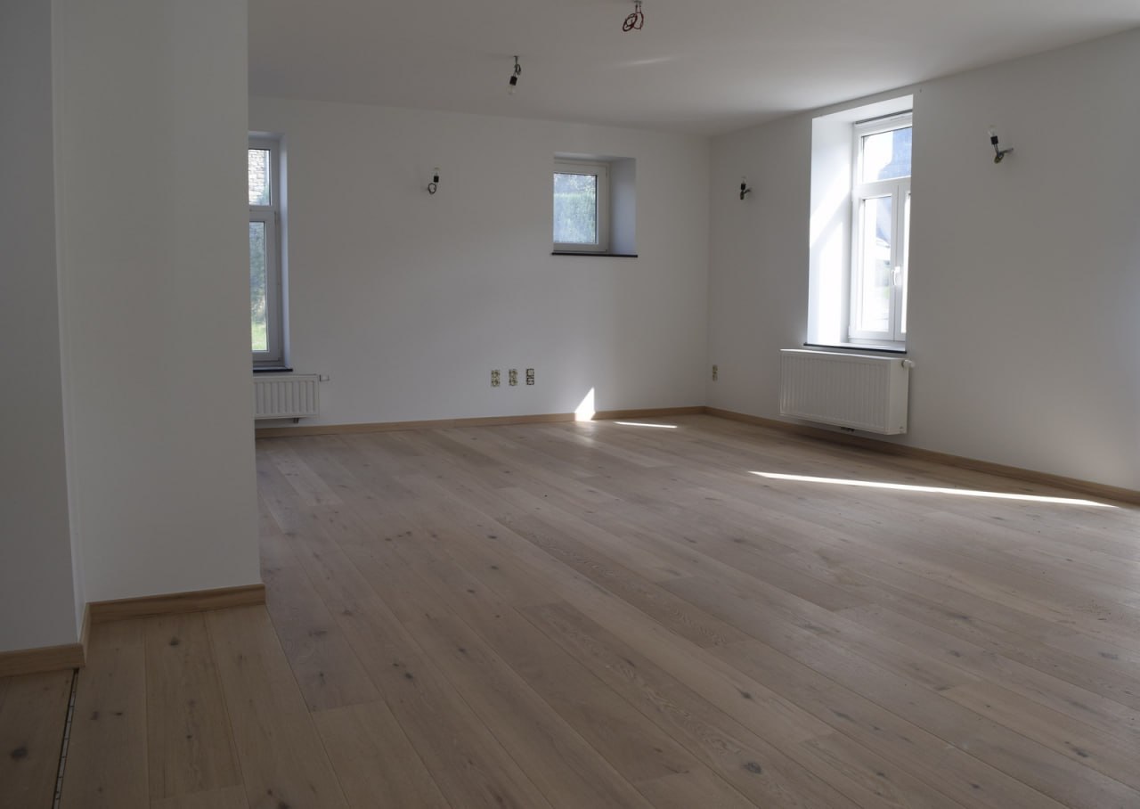Plancher chêne clair — grand séjour ouvert avec multiples fenêtres