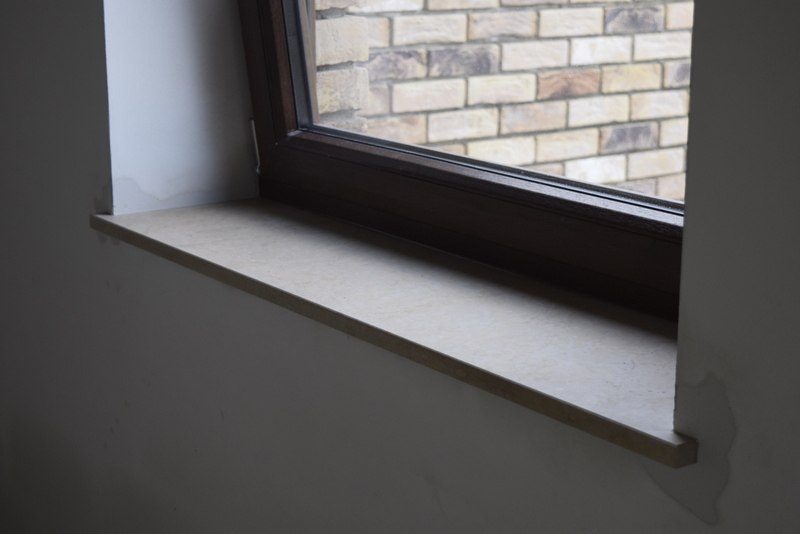 Tablette de fenêtre — appui enduit beige, vue sur mur en pierres